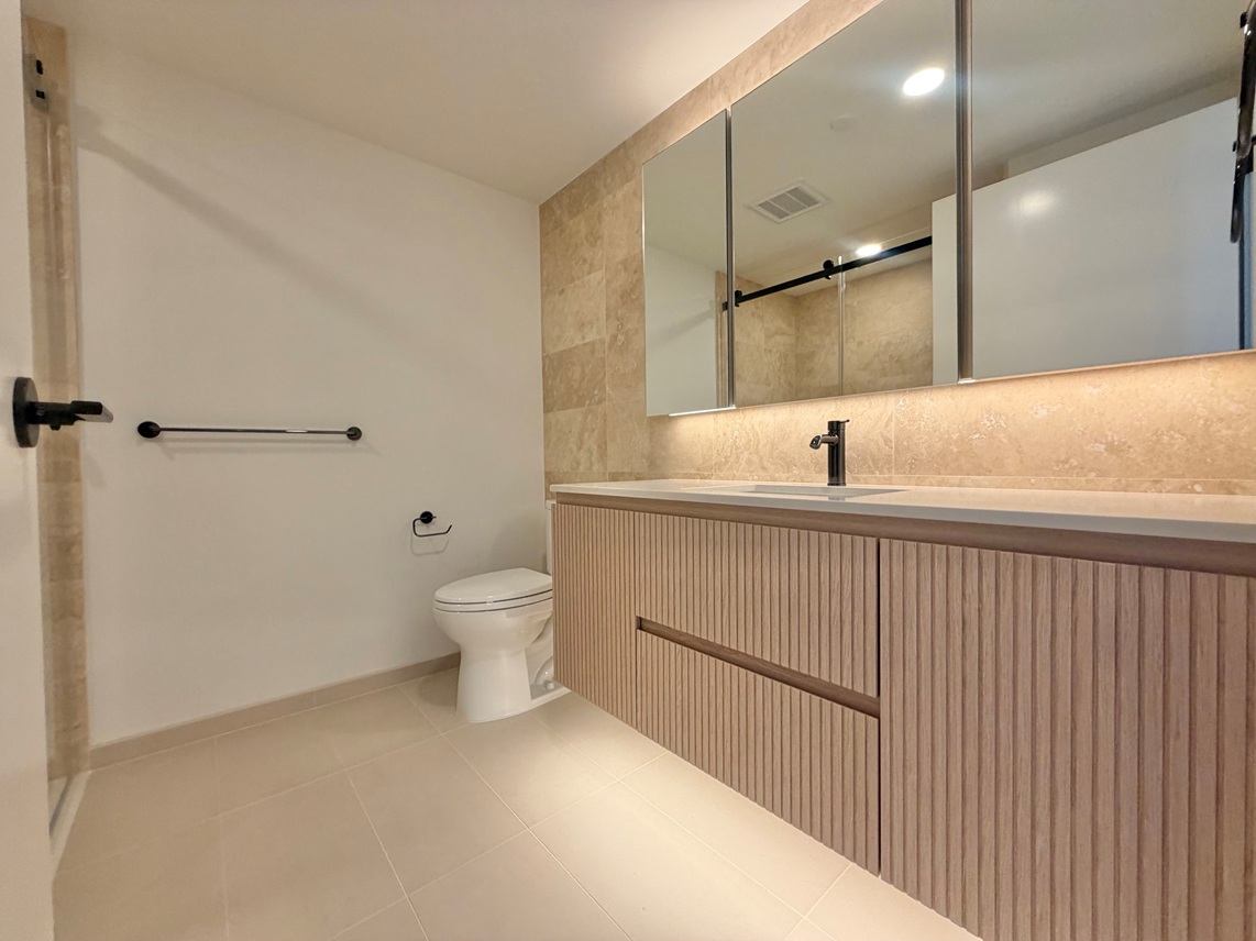 A bathroom with a toilet, sink, and mirror.